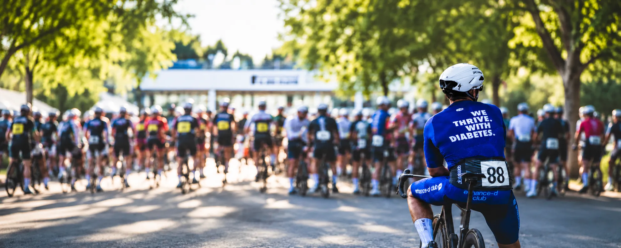 A rider in Enhance-d Club kit waiting at the start line of a cycling event, 'We thrive with diabetes' printed on his jersey